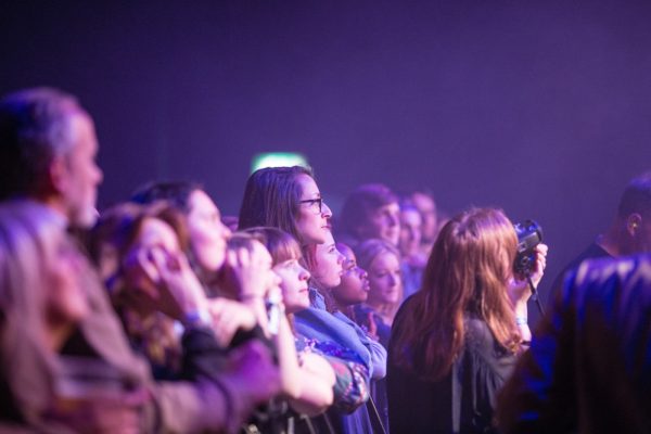 Members of an audience standing and looking forward