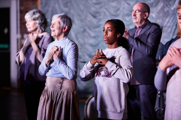 Older people and young girl facing camera with hands crossed over their chests