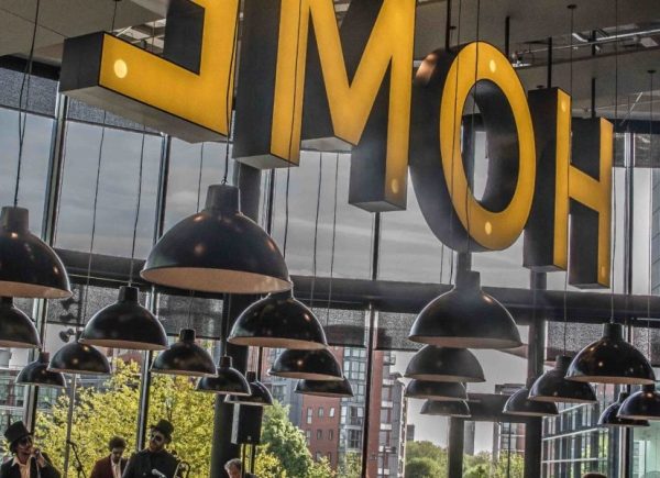 Inside the main foyer at Home Manchester with a large sign with individual letters spelling HOME surrounded by hanging lights.