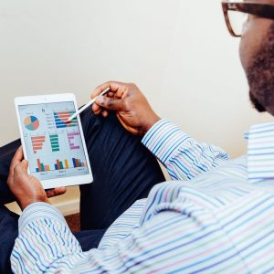 Man working on a tablet. On the tablet screen are graphs and pie charts