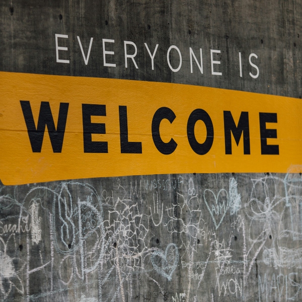 A wall covered in graffiti and the words Everyone is Welcome in capital letters.