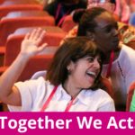 A smiling person sat in an auditorium with hand raised. Words: Togther We Act