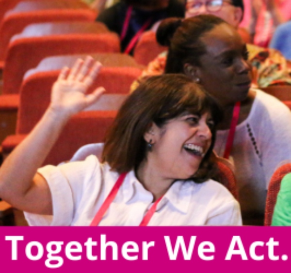 A smiling person sat in an auditorium with hand raised. Words: Togther We Act