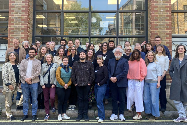 A large group of people standing in rows in front of a red brick building 