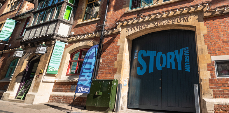 The entry to the Story Museum with large glass doors and the striking new logo in blue with the text Story Museum